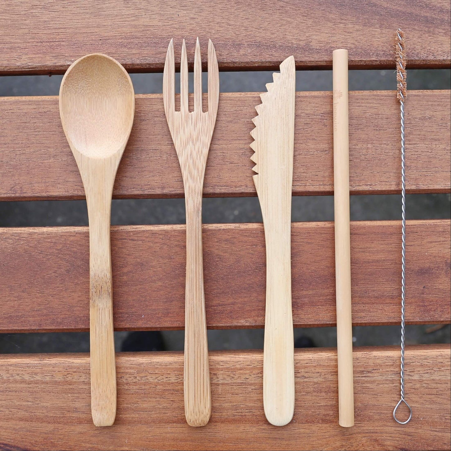 reusable sustainable bamboo cutlery set with fork, spoon, knife and straw on top of a wood table