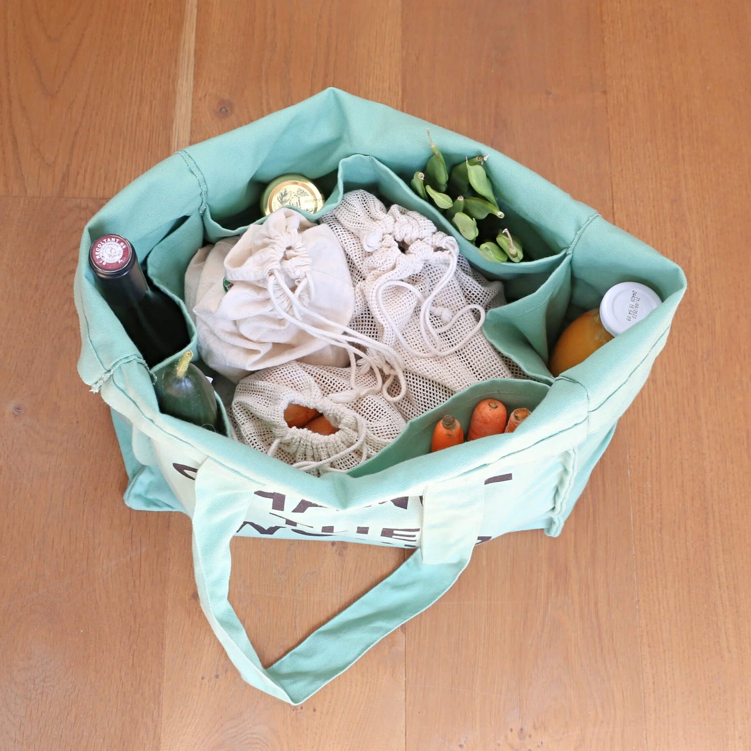 zero waste grocery bag multi pocket with 6 sleeves inside made of organic green cotton with the sentence: small acts change the world being showed inside