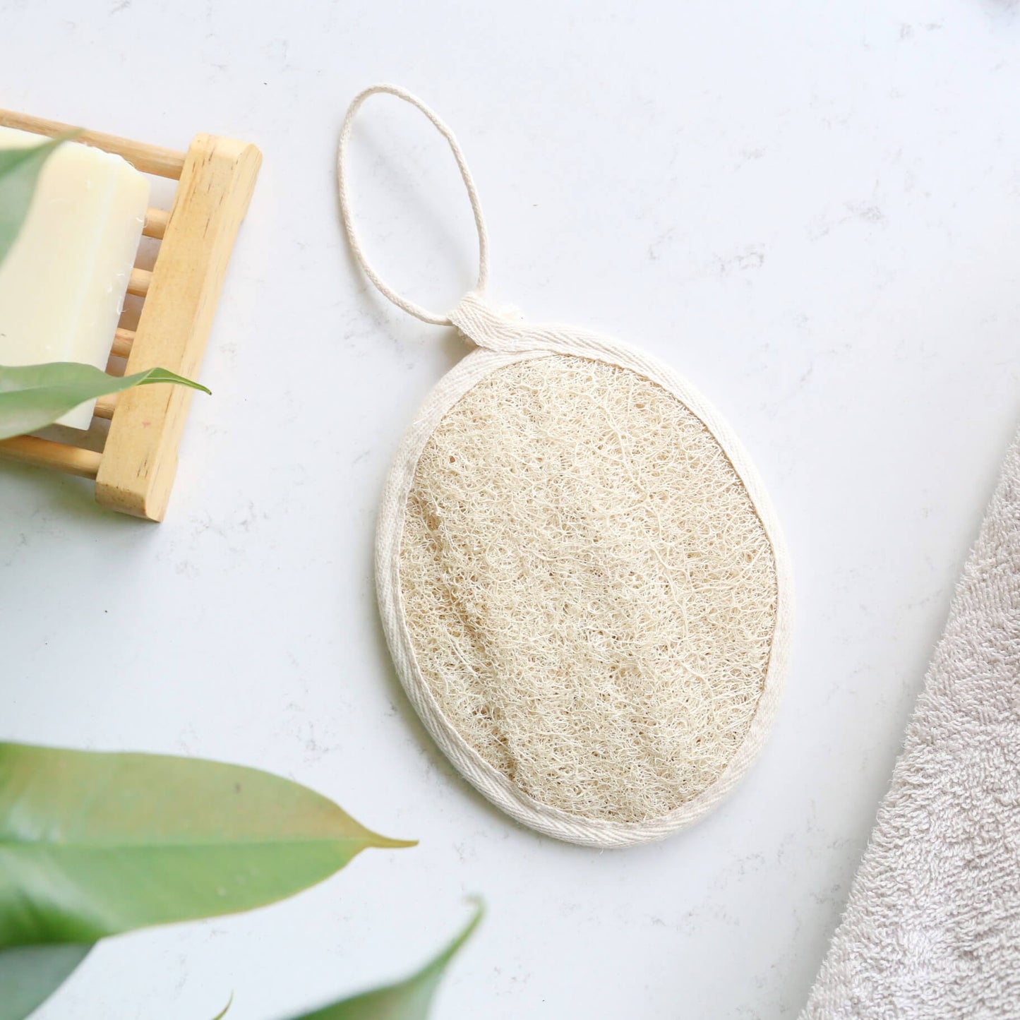 Loofah pad sponge made of natural plant and with a rope to hang on the shower showing on top of a table