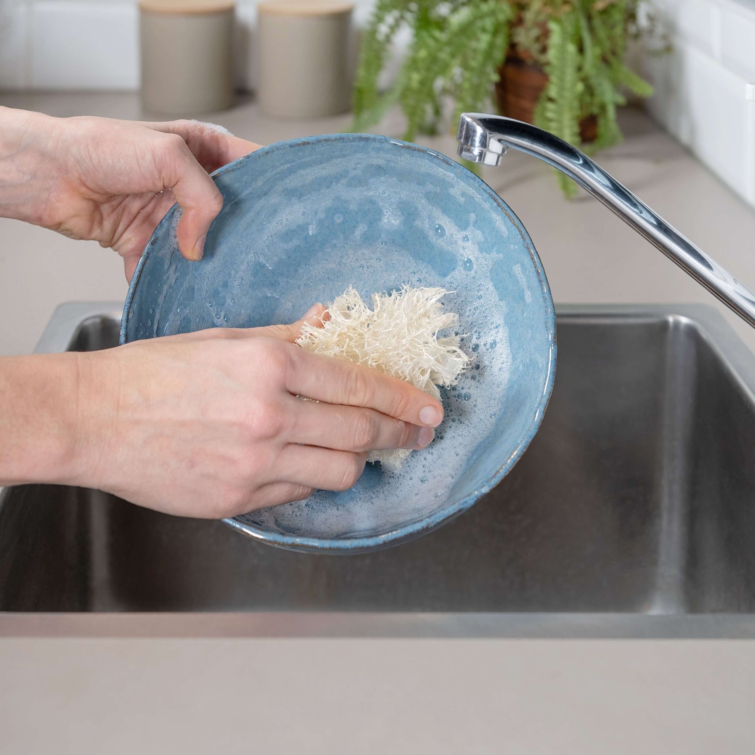 Plastic-free loofah kitchen sponge in action, washing dishes sustainably for a zero-waste clean