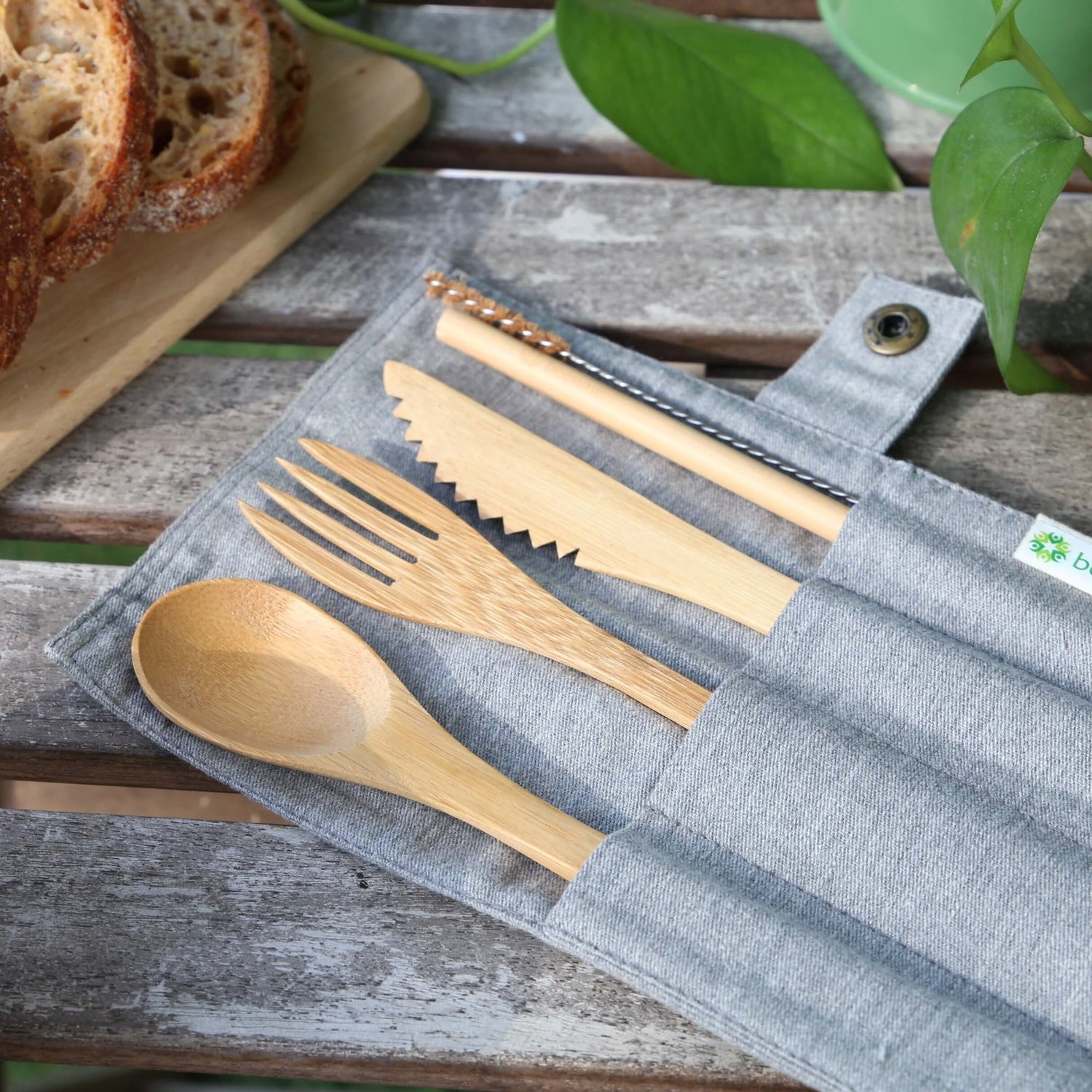 reusable eco-friendly bamboo cutlery set inside a cotton travel pouch on top of a picnic table from beewise