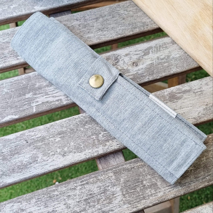 reusable sustainable bamboo cutlery set inside a closed cotton travel pouch on top of a picnic table from beewise