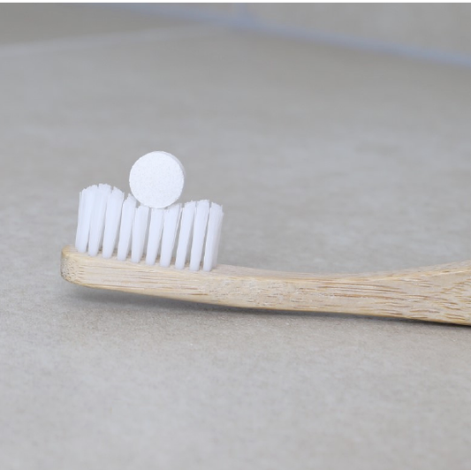 toothpaste tablet in a white bristles bamboo toothbrush