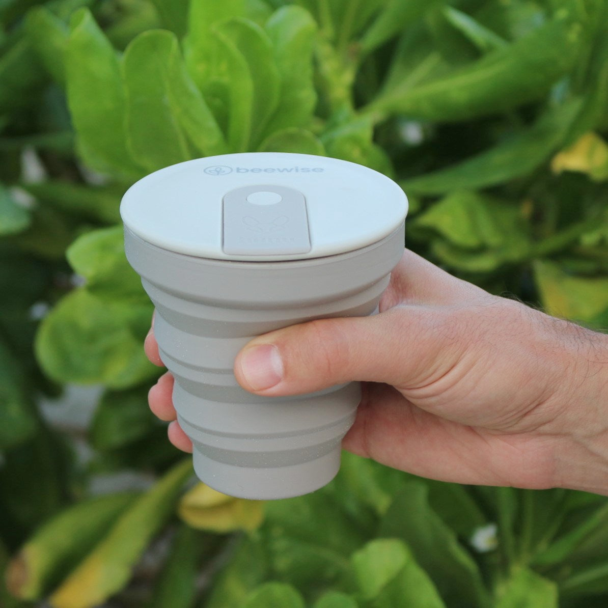 collapsible travel silicone cup  hunu with beewise grey warm colour taken by a man hand