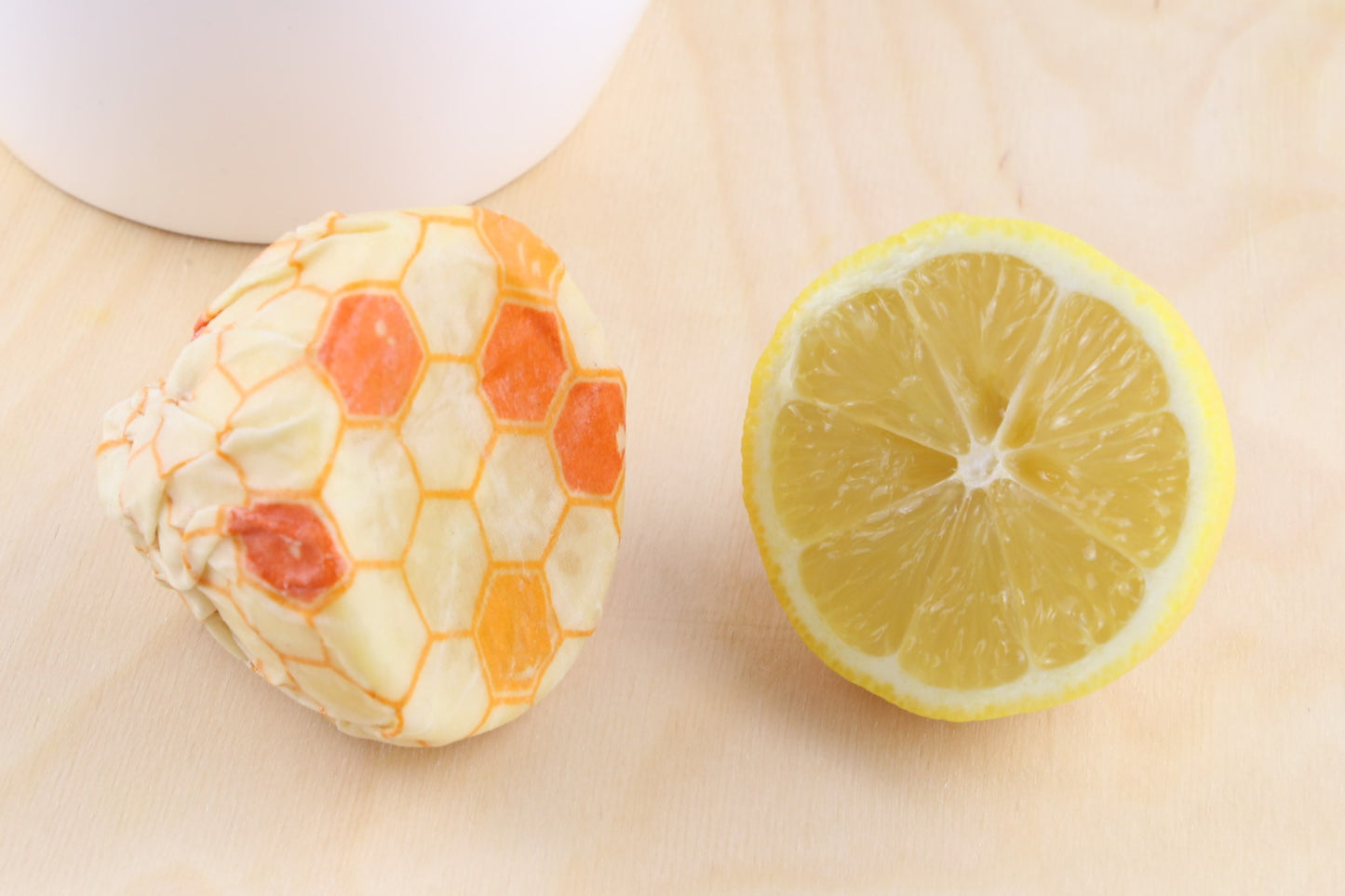 beeswax food wrap hive pattern from beewise amsterdam being used to wrap half lemon at the table