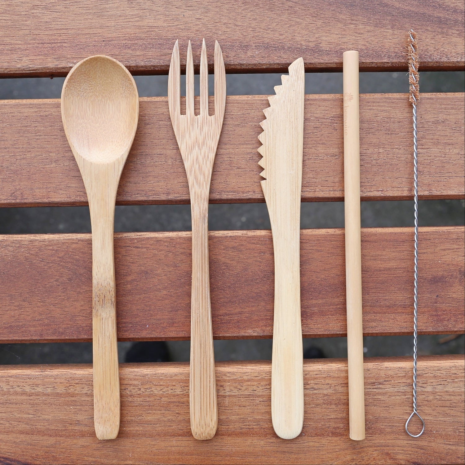 bamboo fork, spoon, knife and straw on top of a wood table
