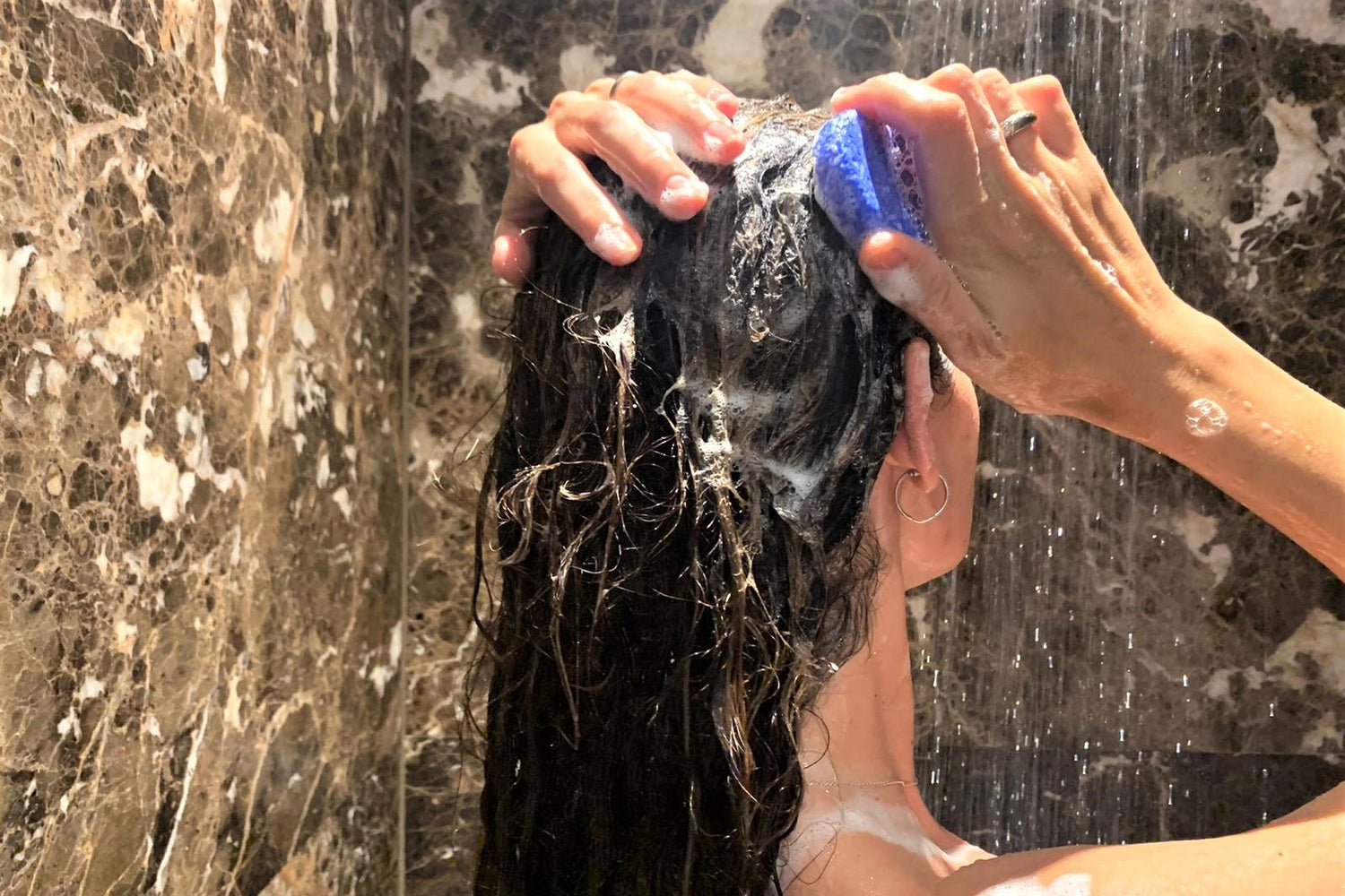 woman taking a shower and washing her hair with a lavender shampoo bar beewise 